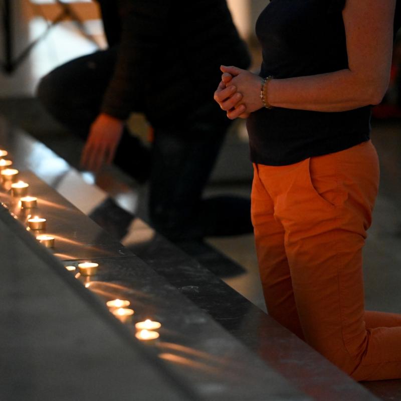 Menschen knien vor einem Kerzenaltar bei der Initiative 'Nightfever' in der Domkirche Sankt Eberhard beim 102. Deutschen Katholikentag am 29. Mai 2022 in Stuttgart.